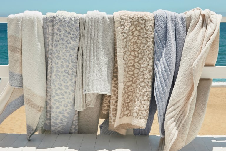 A row of cozy Island Soft® throws, now at a reduced price for a limited time at Tommy Bahama